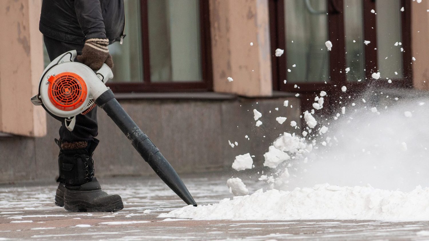 Man cleans street from snow with blower